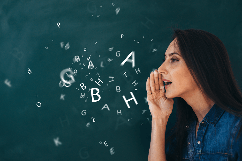 a woman with her hand next to her mouth speaking, with random letters floating around her