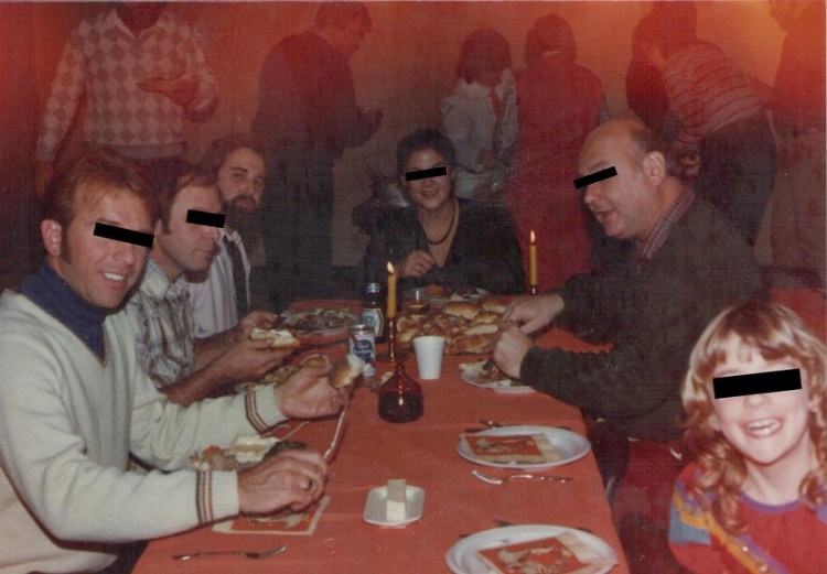 Photo of a family sitting together eating at a funeral (Black-Level Event). Everyone's eyes are censored except a bearded man in his thirties at the far end of the table.
