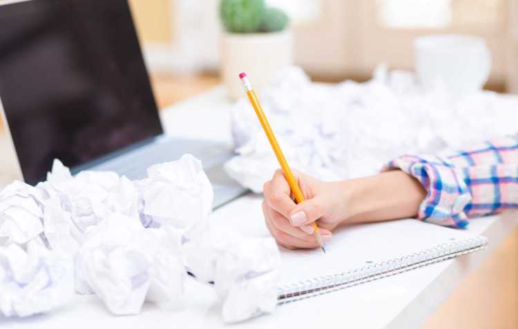 woman-writing-on-a-notebook-with-crumpled-paper-balls-2