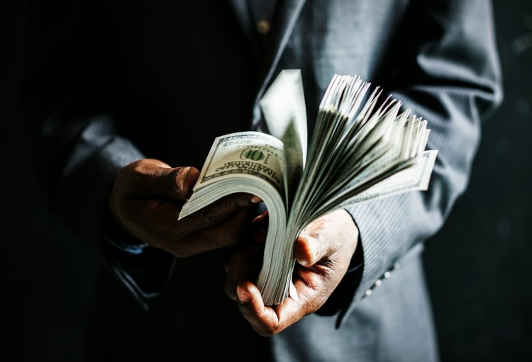 businessman thumbing through a fat stack of cash