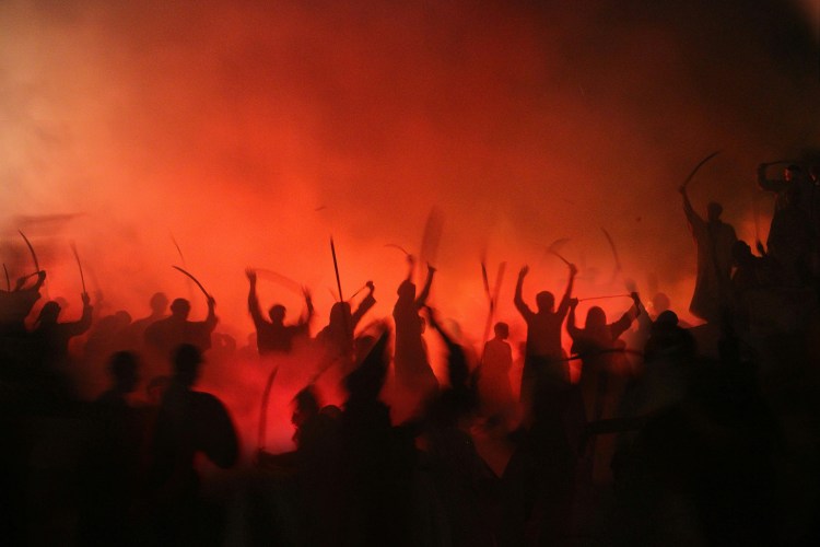 crowd of people with swords in a red haze
