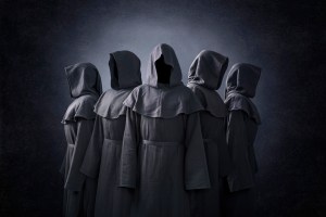 Group of five scary figures in hooded cloaks in the dark; grey background