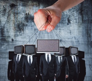 Hand holding TV headed businessmen on strings. Mass misinformation concept.
