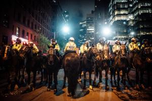 Photo of a squad of police in yellow vests on horseback in the middle of a city