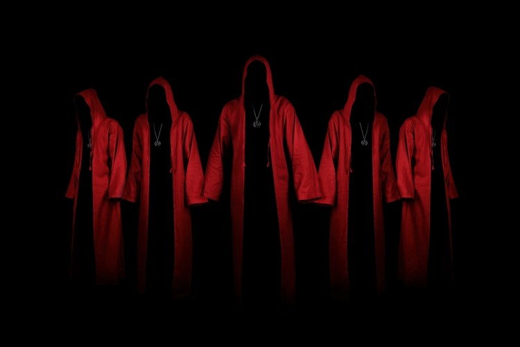 group of mysterious people in red hooded cloaks against a black background