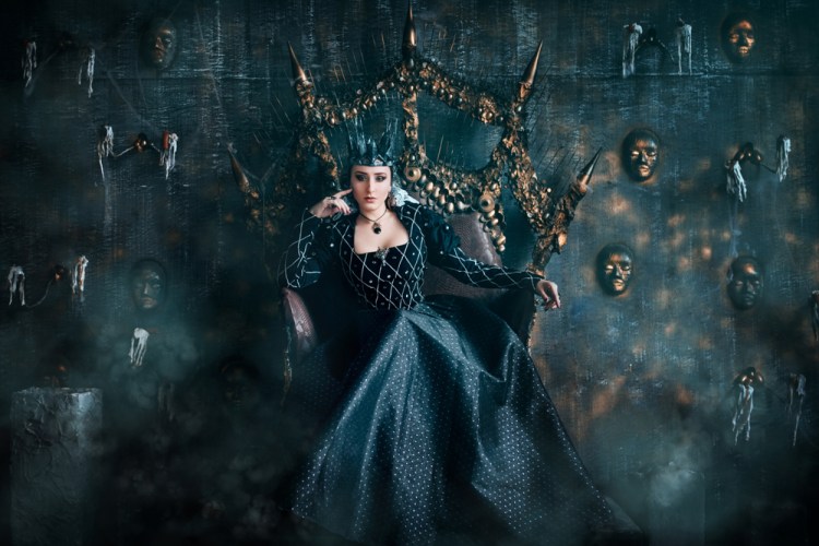 fantasy plot idea, an evil queen in a black dress seated on a throne with masks on the wall behind her