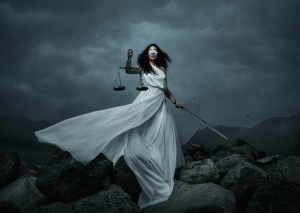 young blindfolded woman with scale and sword over the dramatic sky