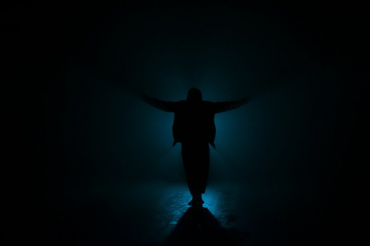 a person standing in the dark with their arms outstretched