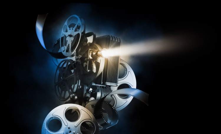 Cinema background with movie projector and film reels on a dark background