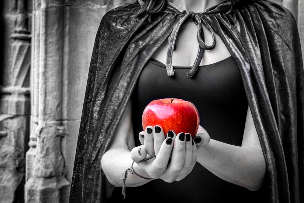 black and photo photo of an evil queen holding a bright red apple