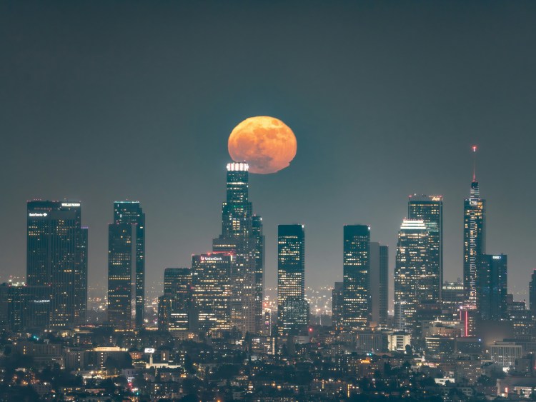 image of a city skyline at night with an orange moon in the sky