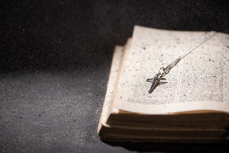 open holy bible with a catholic cross and ashes in dark with sunlight