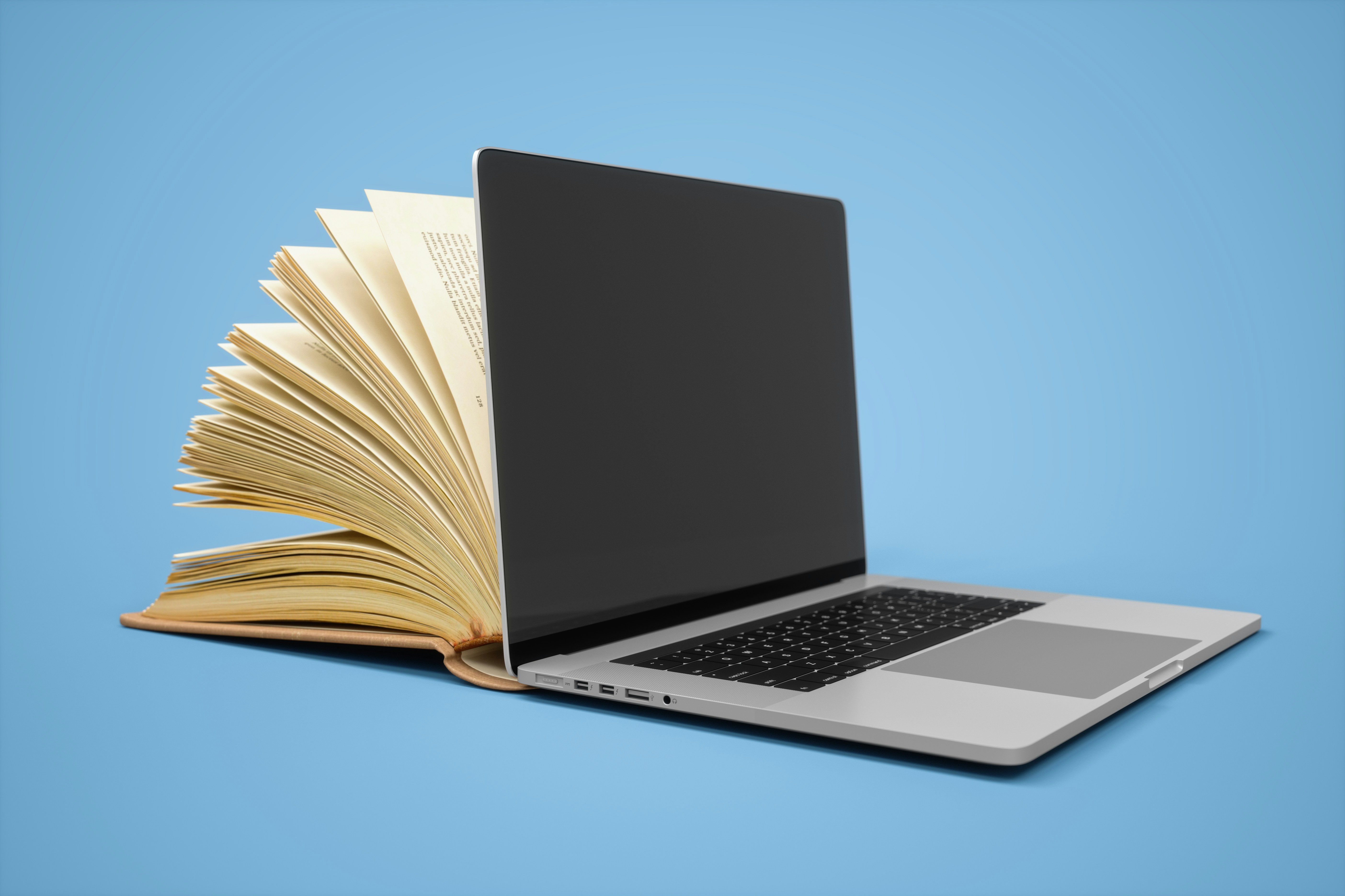 book is better than movie concept; a laptop against a blue background with an open book coming out of the back of the screen